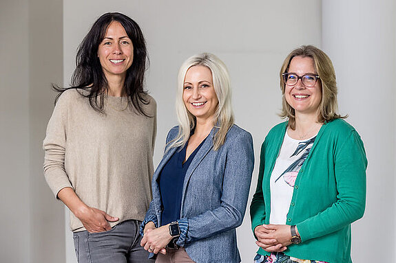 Sozialdienst Das Bild zeigt drei Frauen, die in die Kamera lächeln.