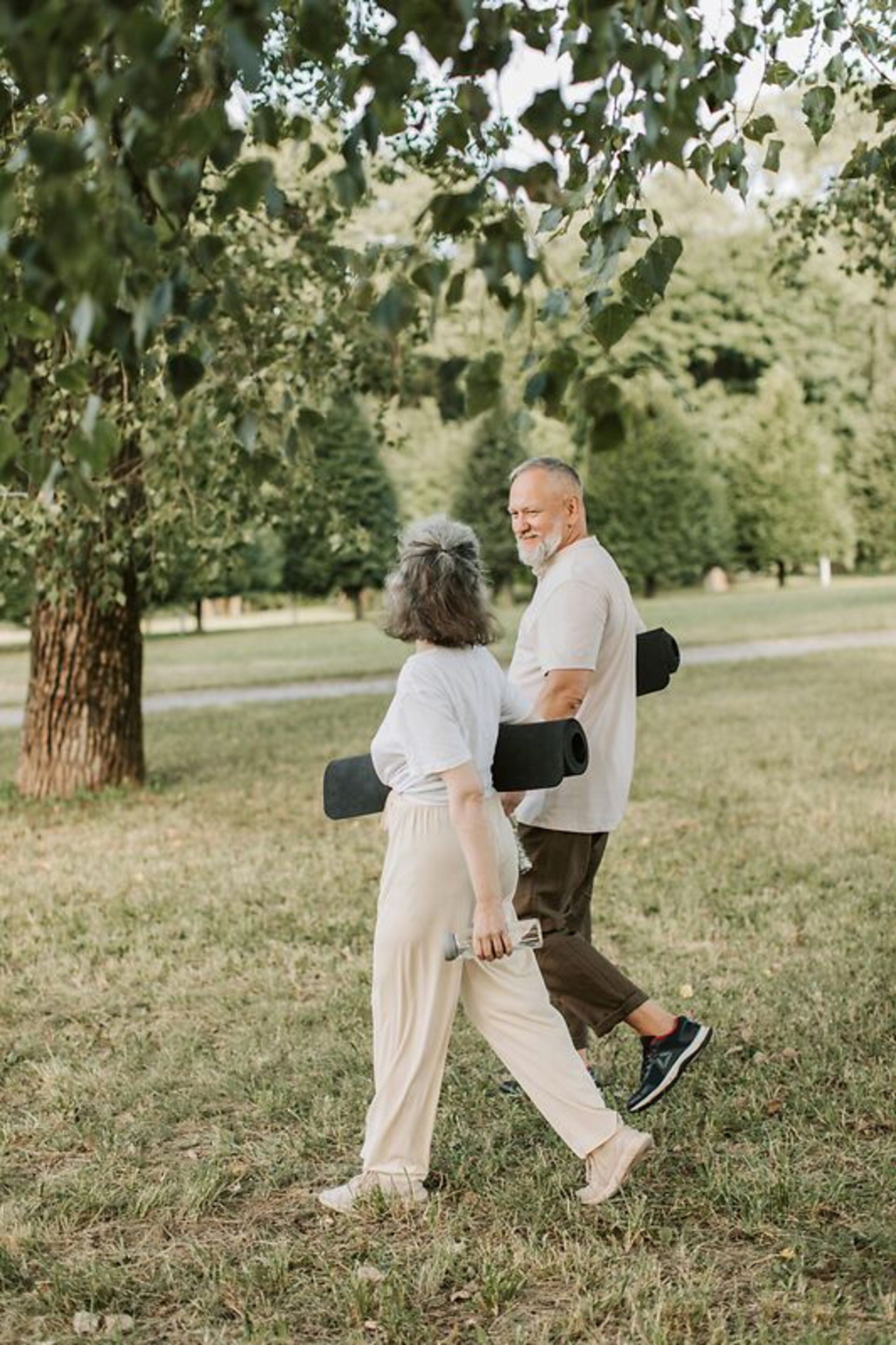 Patienten Outdoor Gymnastik Ein Mann und eine Frau laufen mit Gymnastikmatten auf einer Wiese.