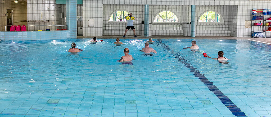 Ein Therapeut leitet eine Wassergymnastik-Gruppe an.