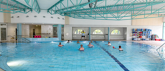 Ein Therapeut leitet eine Wassergymnastik-Gruppe an.