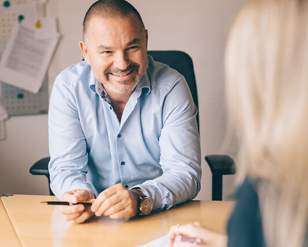 Maximilian Koehler Dr. Köhler sitzt lächeln am Schreibtisch mit einer Patientin.