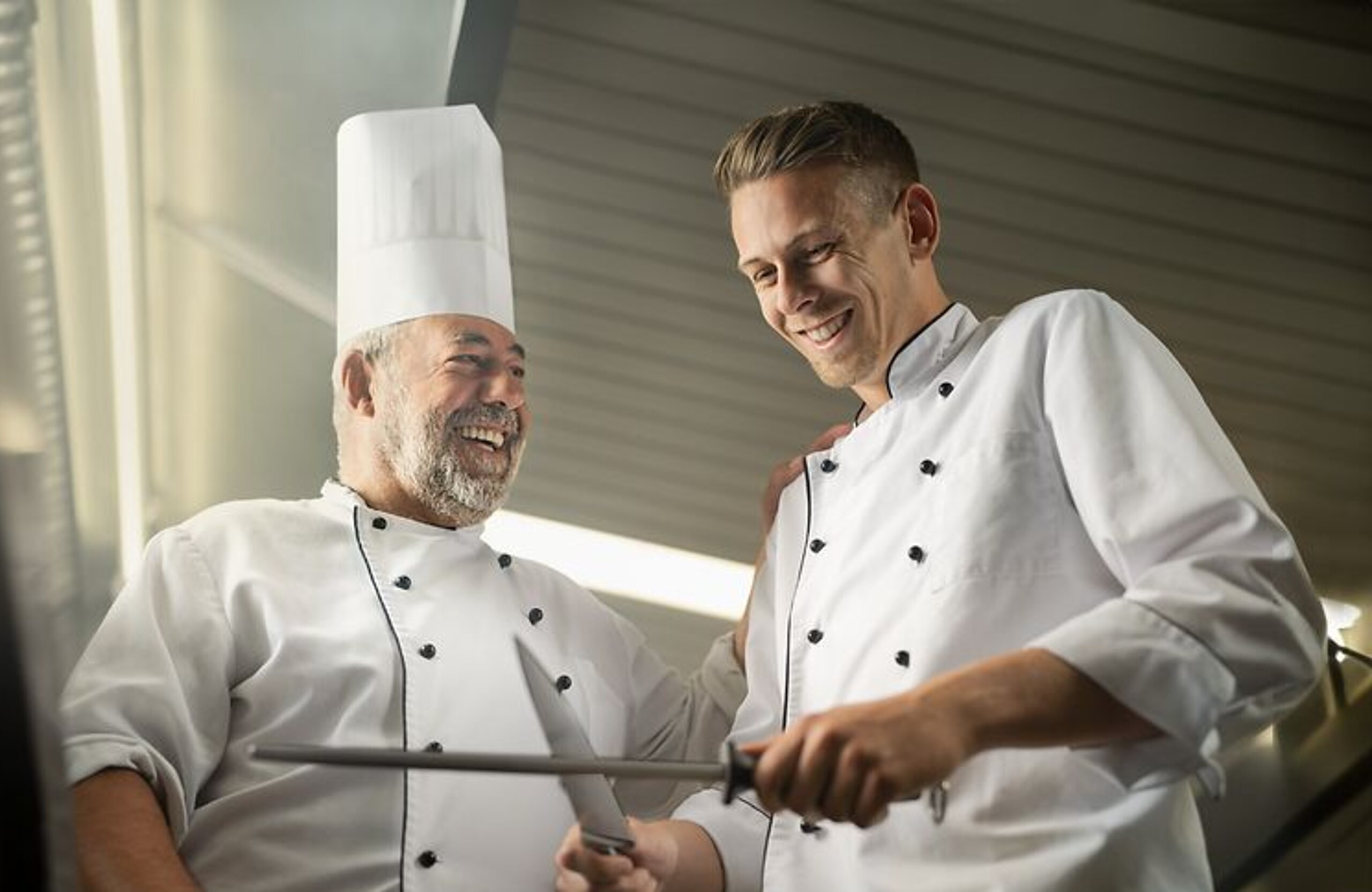 Respekt Ein alter Koch zeigt einem jungen Koch etwas.