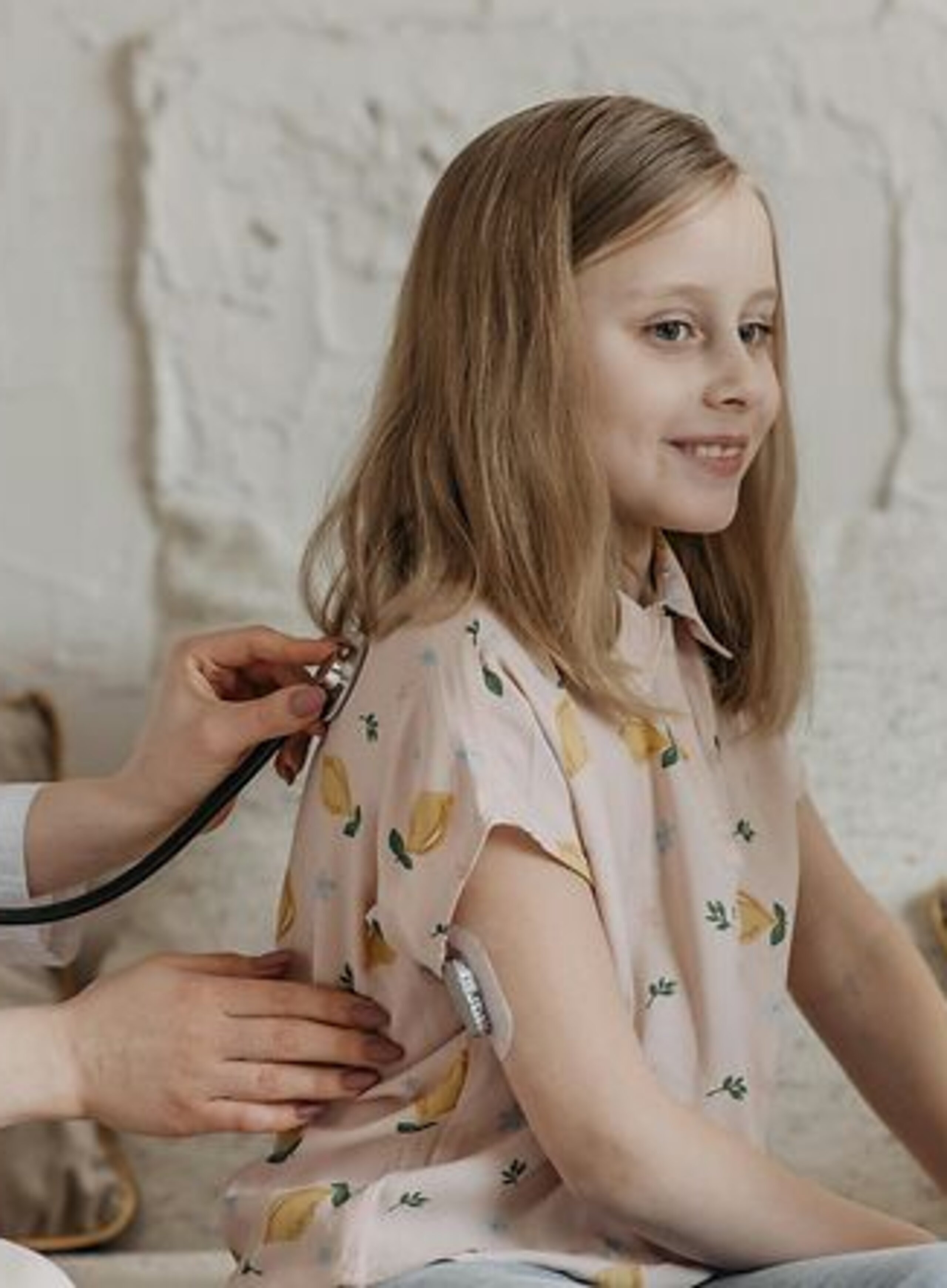 Untersuchung Kind Eine Ärztin horcht den Rücken eines Mädchens per Stethoskop ab.