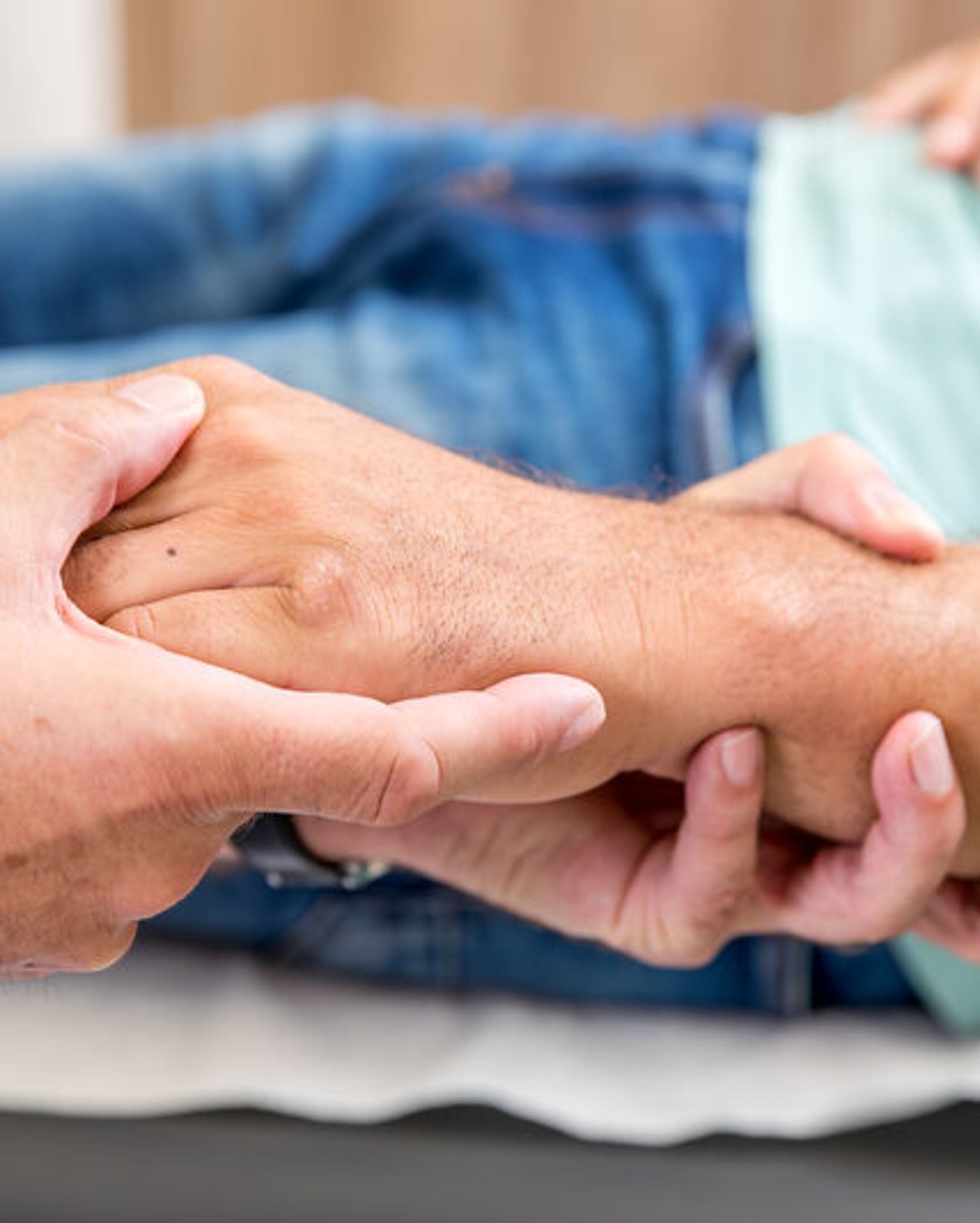 Ein Arzt umfasst die Hand eines Patienten.