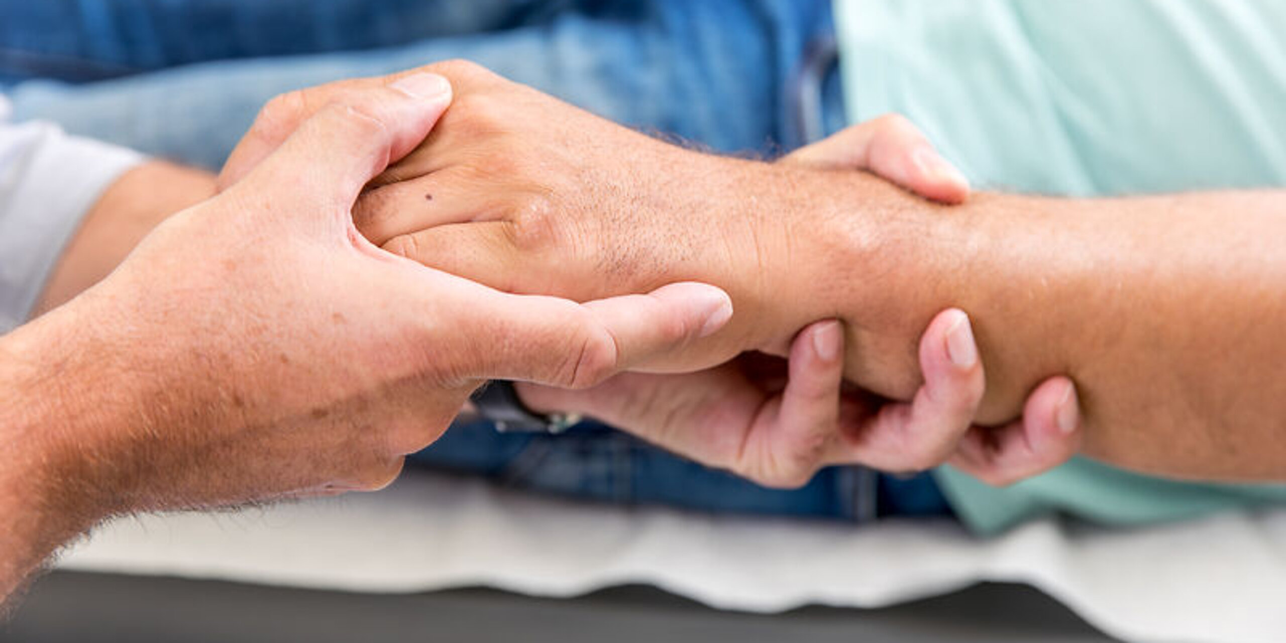 Ein Arzt umfasst die Hand eines Patienten.