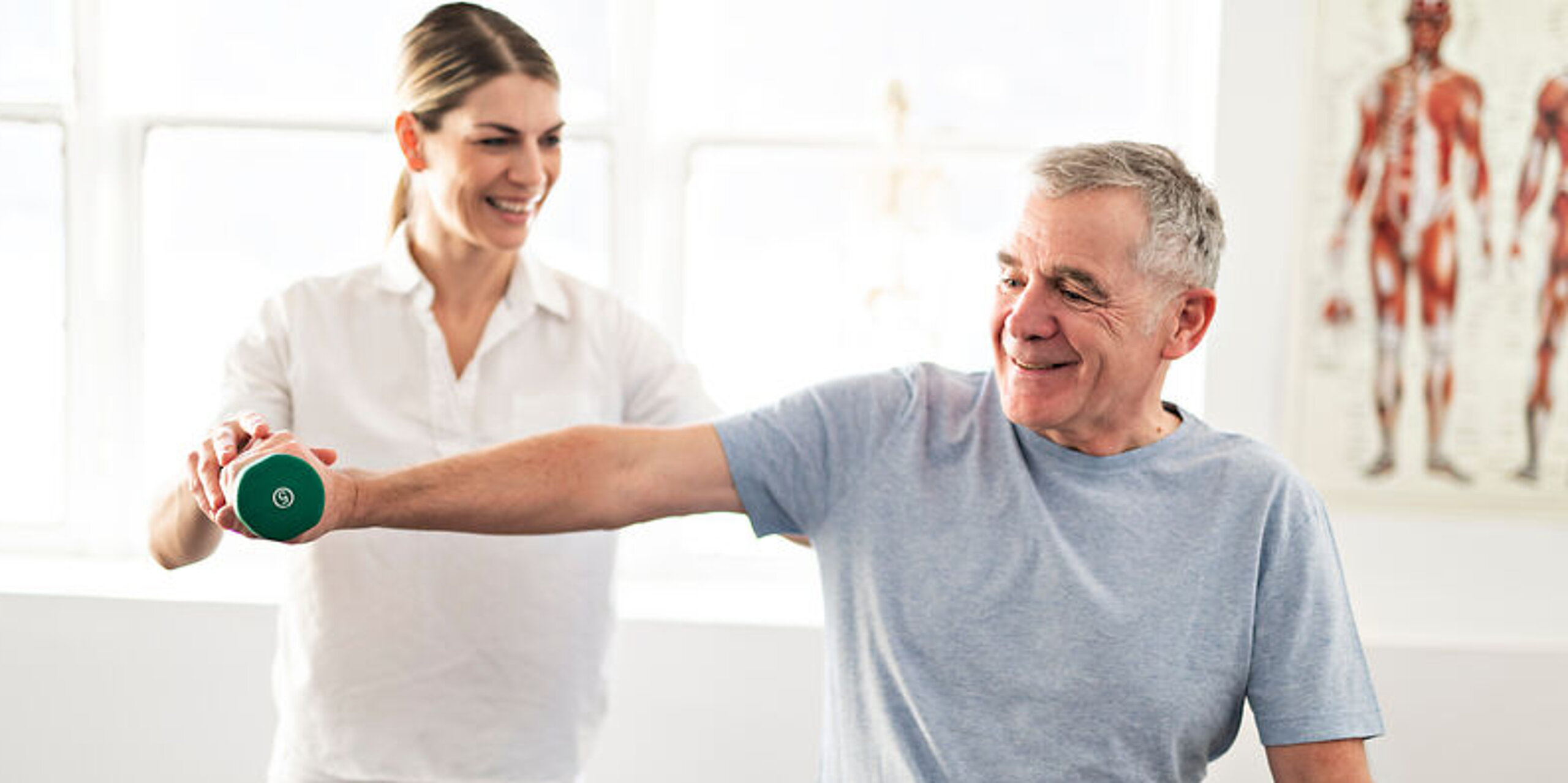 Eine Therapeutin macht Hantelübungen mit einem Patienten.