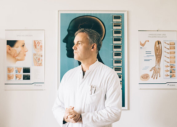 Dr. Dr. Schlomm steht in seiner Praxis.