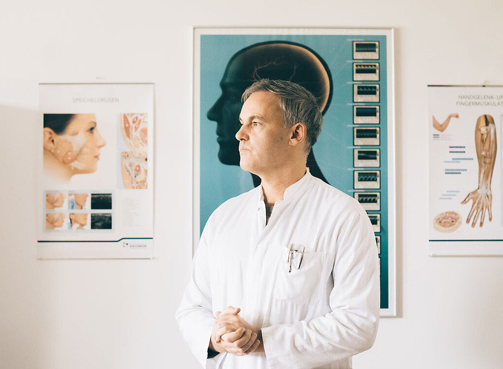 Dr. Dr. Schlomm steht in seiner Praxis.