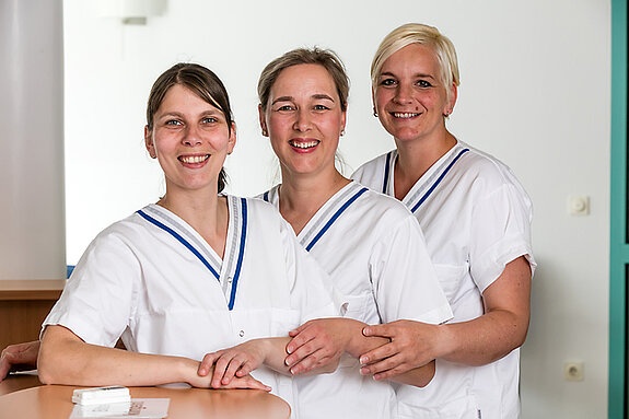 Pflegeteam Drei Pflegerinnen lächeln in die Kamera.