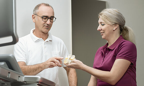 Ein Arzt zeigt einer Patientin etwas an einem Knochenmodel.