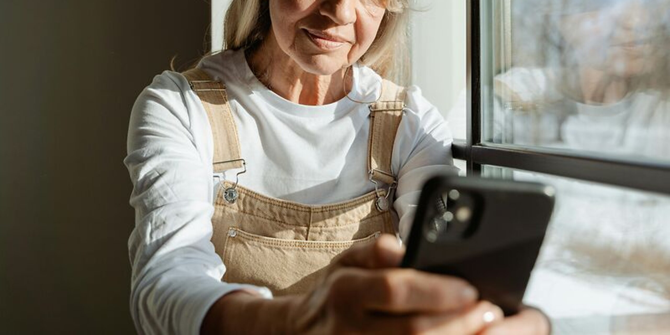 Frau mittleren alters schaut in ihr Mobiltelefon.