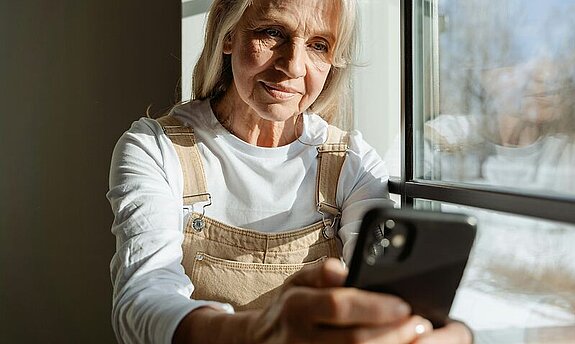 Frau mittleren alters schaut in ihr Mobiltelefon.