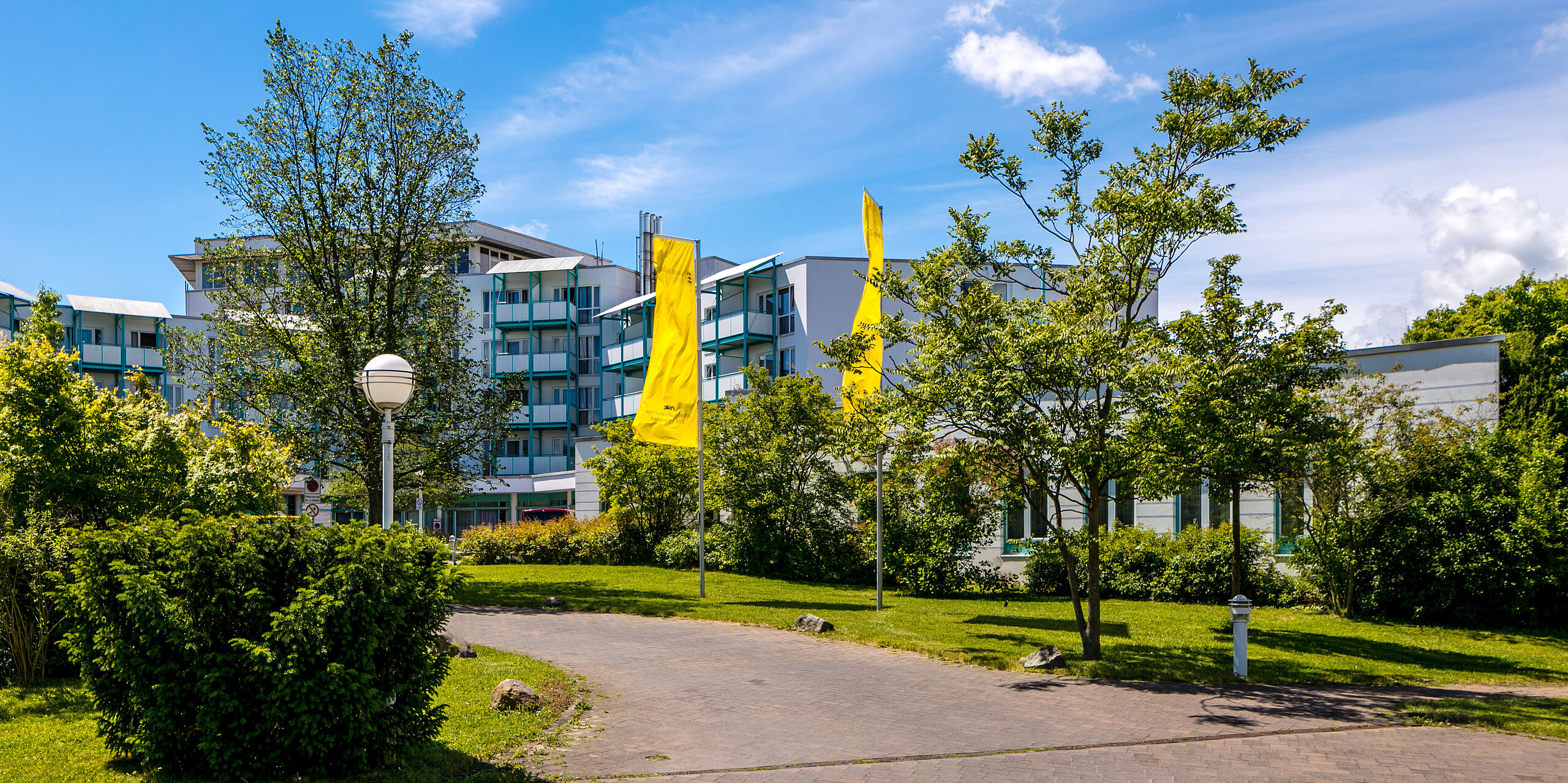 Das Bild zeigt einen gepflasterten Gehweg, der zur Rehabilitationsklinik Bad Salzelmen hinführt.