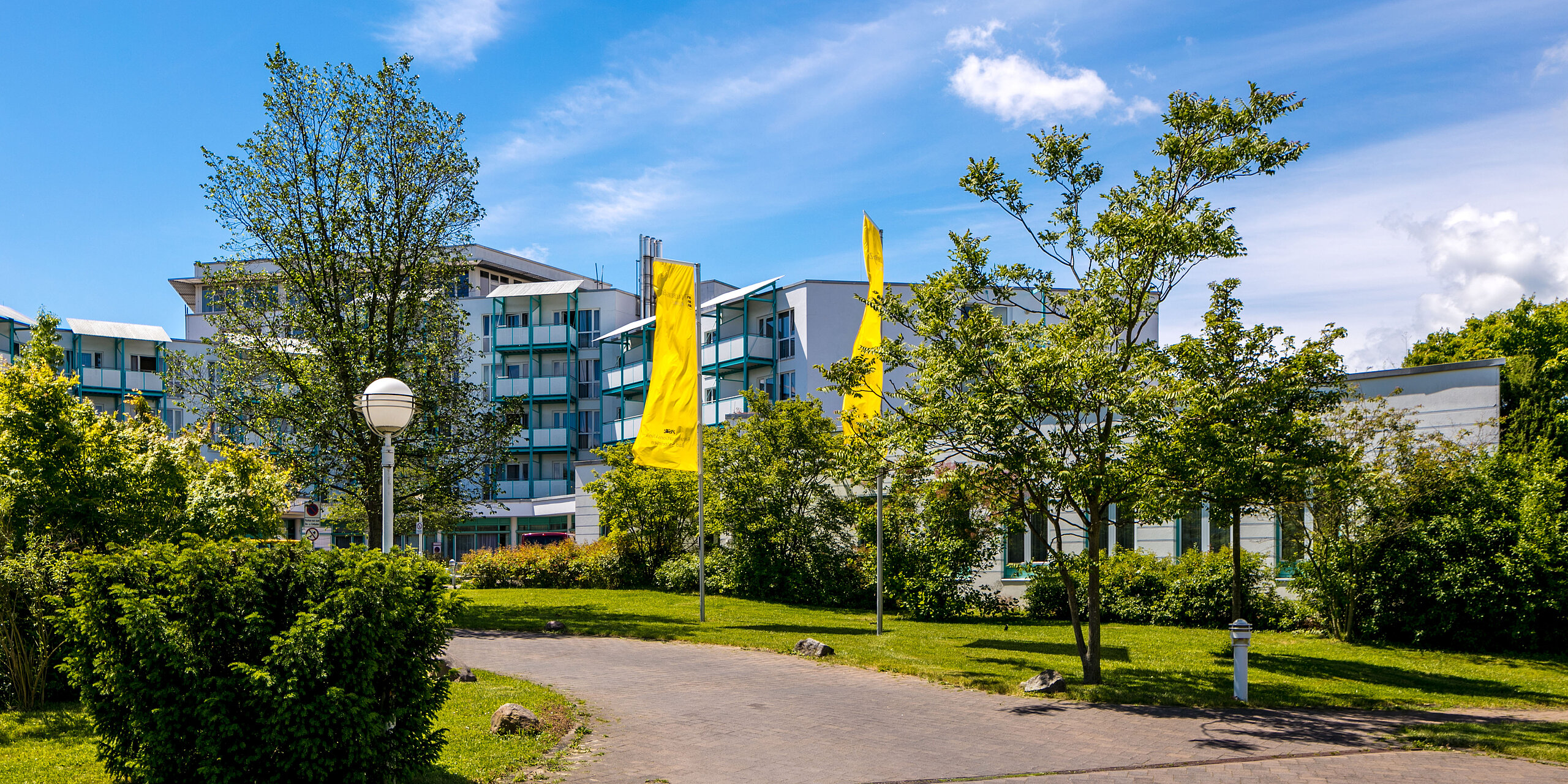 Das Bild zeigt einen gepflasterten Gehweg, der zur Rehabilitationsklinik Bad Salzelmen hinführt.