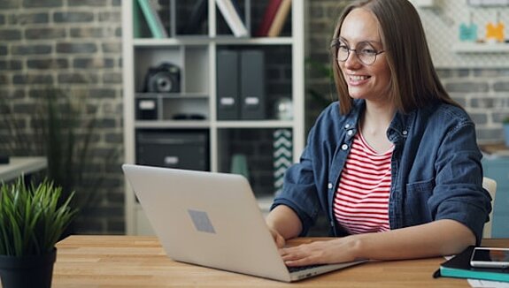 Laptop Frau am Laptop lächelnd.