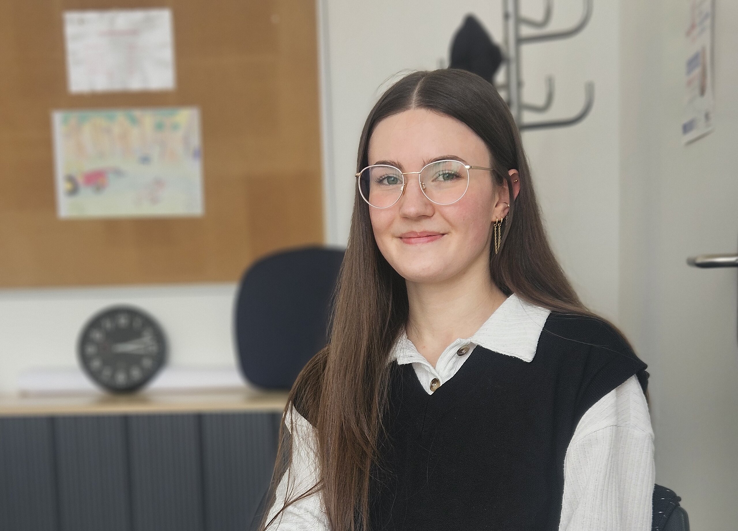Eine Psychologin der KIH sitzt am Schreibtisch und guckt Richtung Kamera während sie einen Kugelschreiber hält.