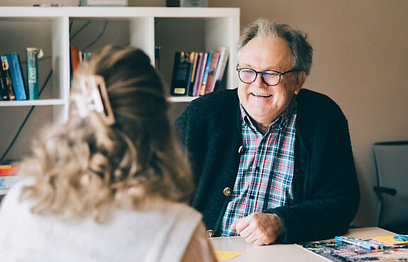 Dr. Holst bei einem Gespräch mit einer Patientin am Schreibtisch.
