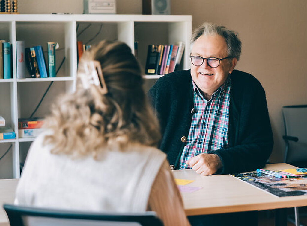 Dr. Holst bei einem Gespräch mit einer Patientin am Schreibtisch.