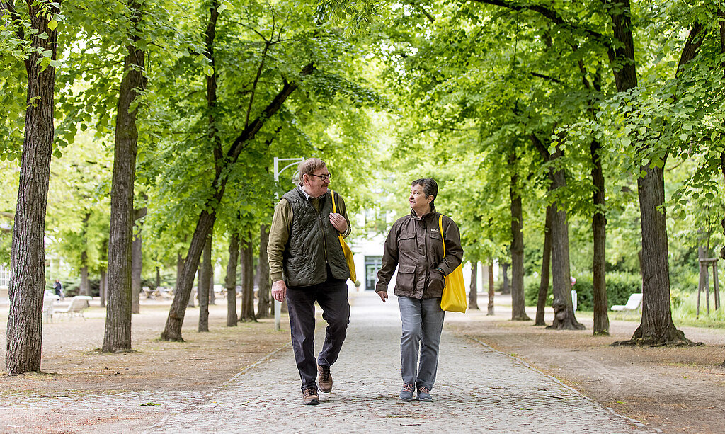 Ein Rehabilitand und eine Rehabilitandin gehen im Kurpark Bad Salzelmen spazieren.