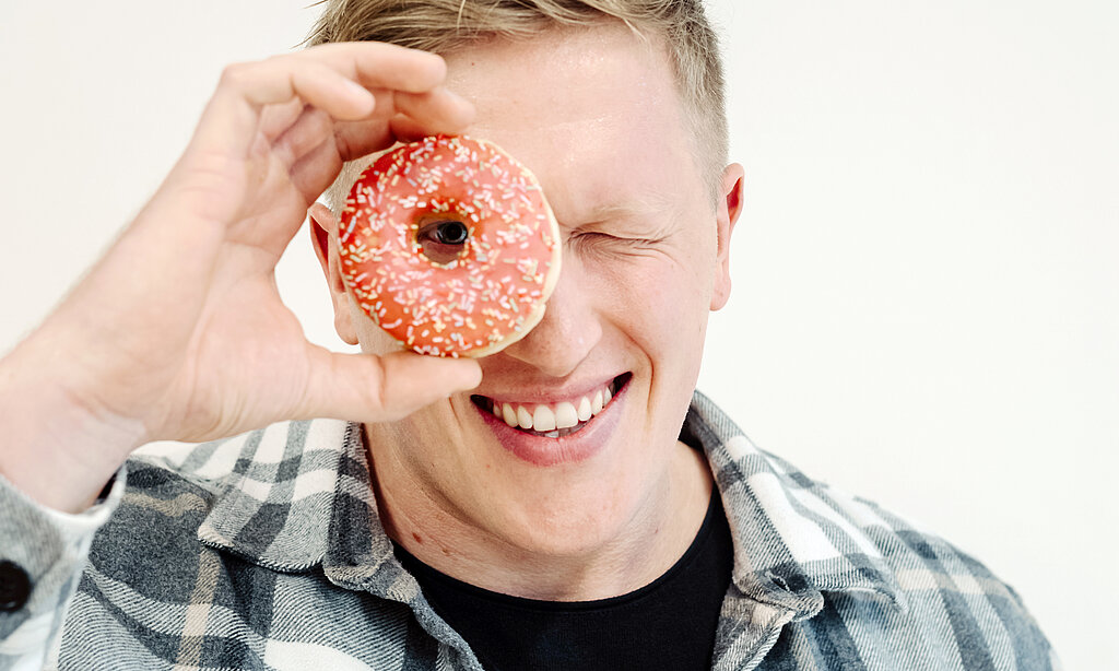 Jan Blaschko sieht mit einem Auge durch einen Donut.
