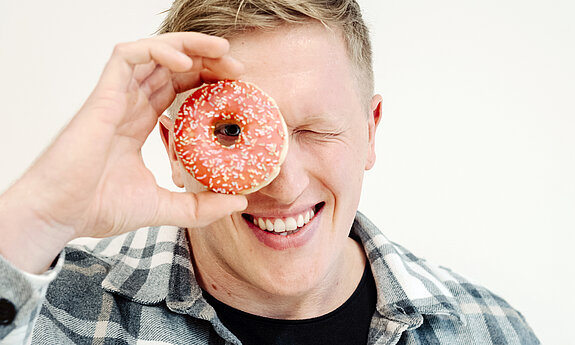 Jan Blaschko sieht mit einem Auge durch einen Donut.
