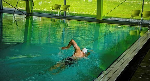 Ein Schwimmer bewegt sich durch Graulen durch das Schwimmbecken eines leeren Hallenschwimmbades