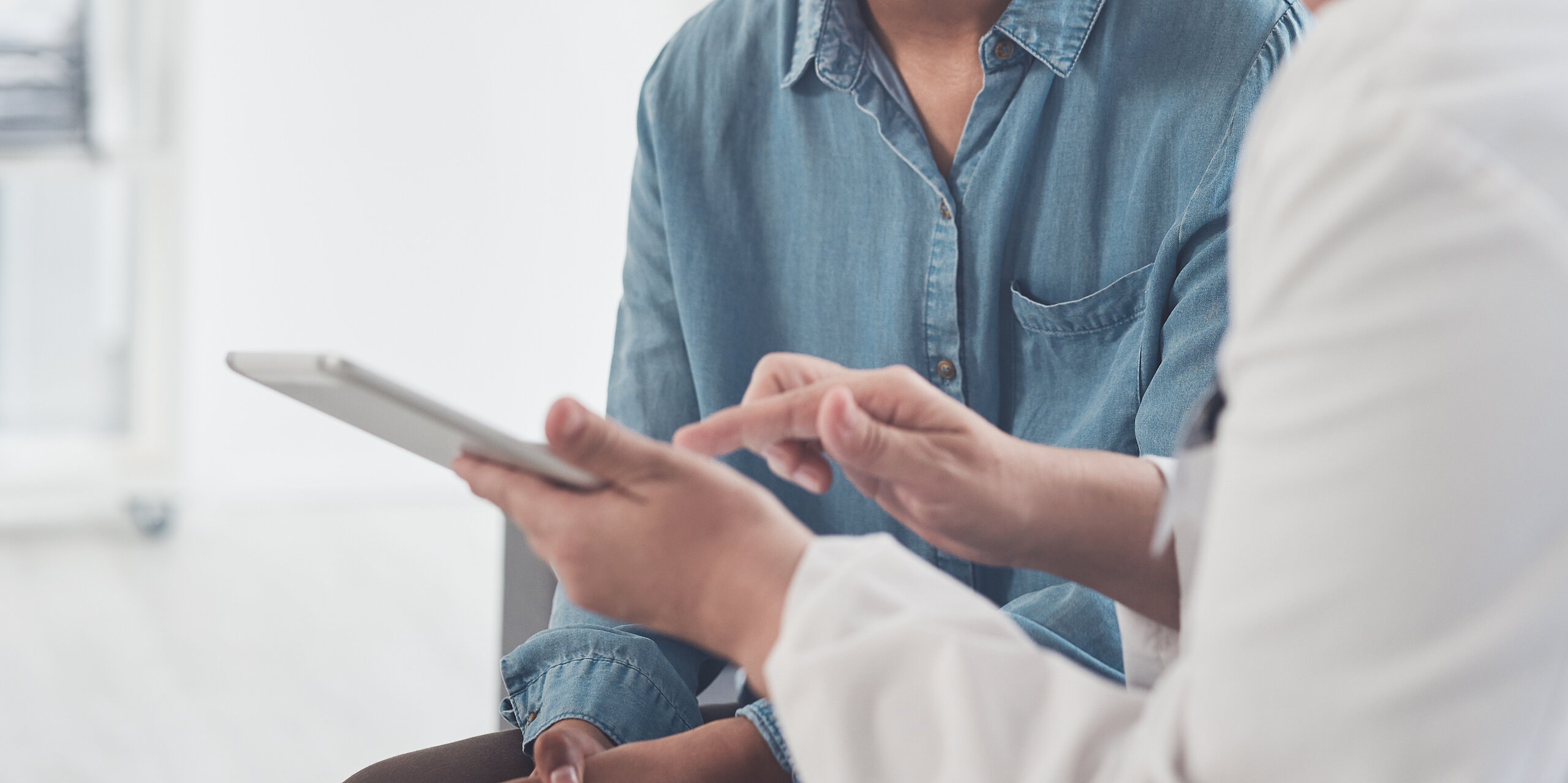Eine Ärztin zeigt einer jungen Patientin etwas an einem Tablet.