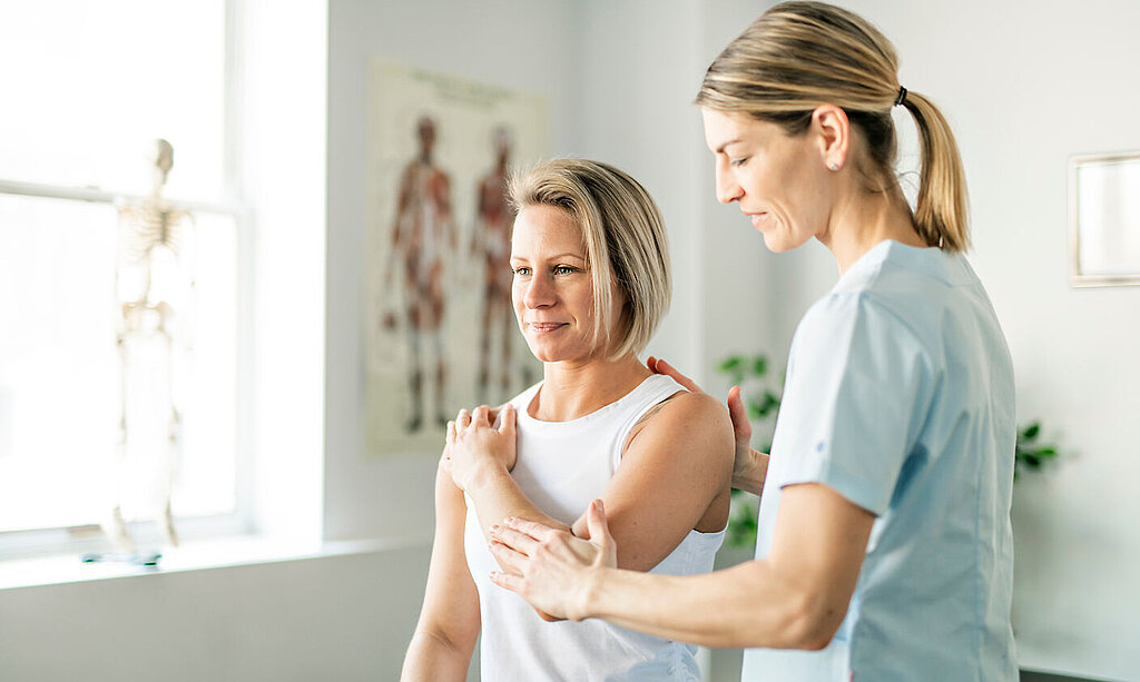 Eine Physiotherapeutin behandelt den Arm einer Patientin.