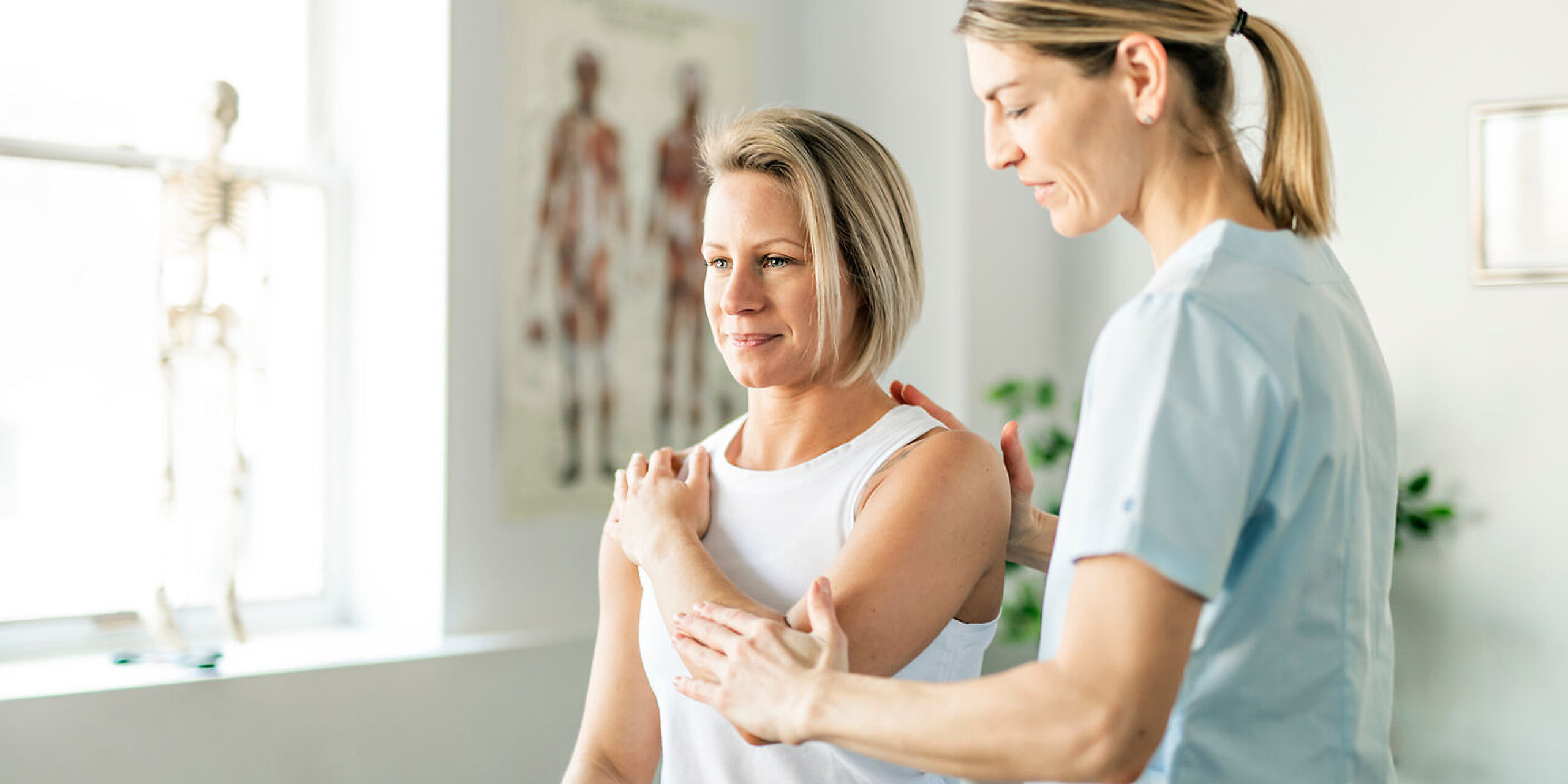 Eine Physiotherapeutin behandelt den Arm einer Patientin.