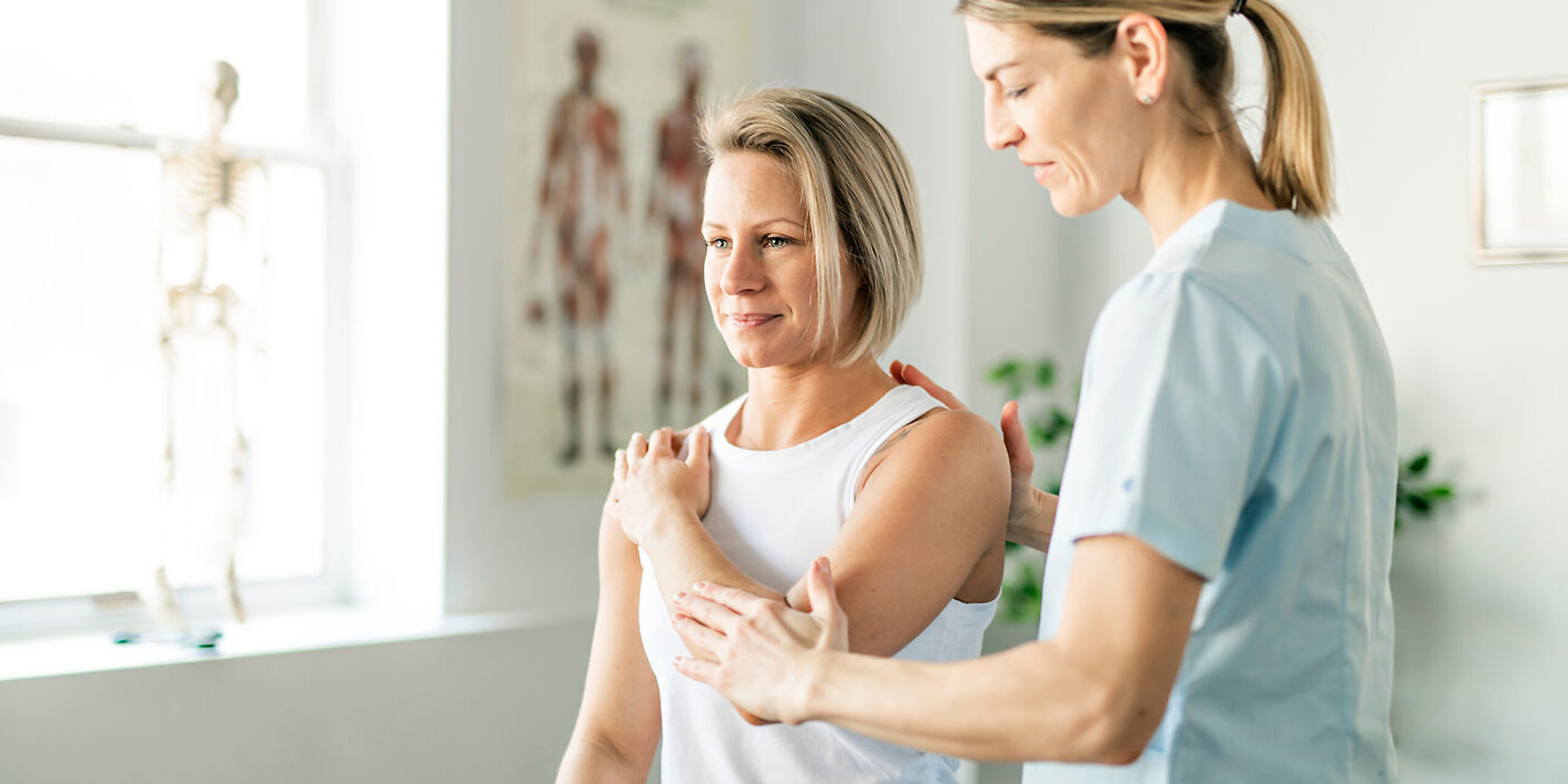 Eine Physiotherapeutin behandelt den Arm einer Patientin.