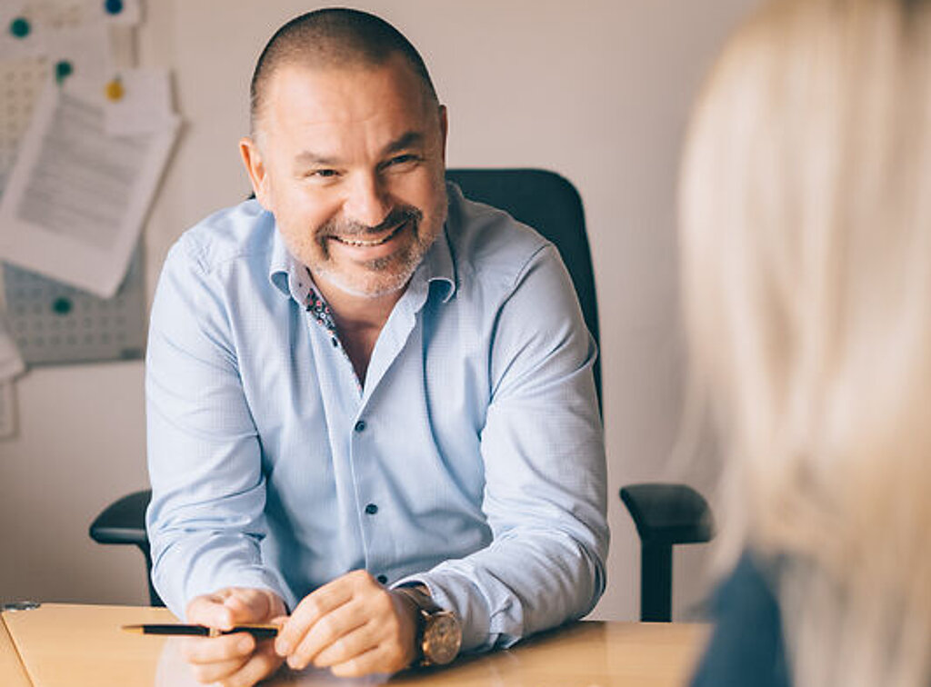 Dr. Köhler berät freundlich eine Patientin am Schreibtisch.
