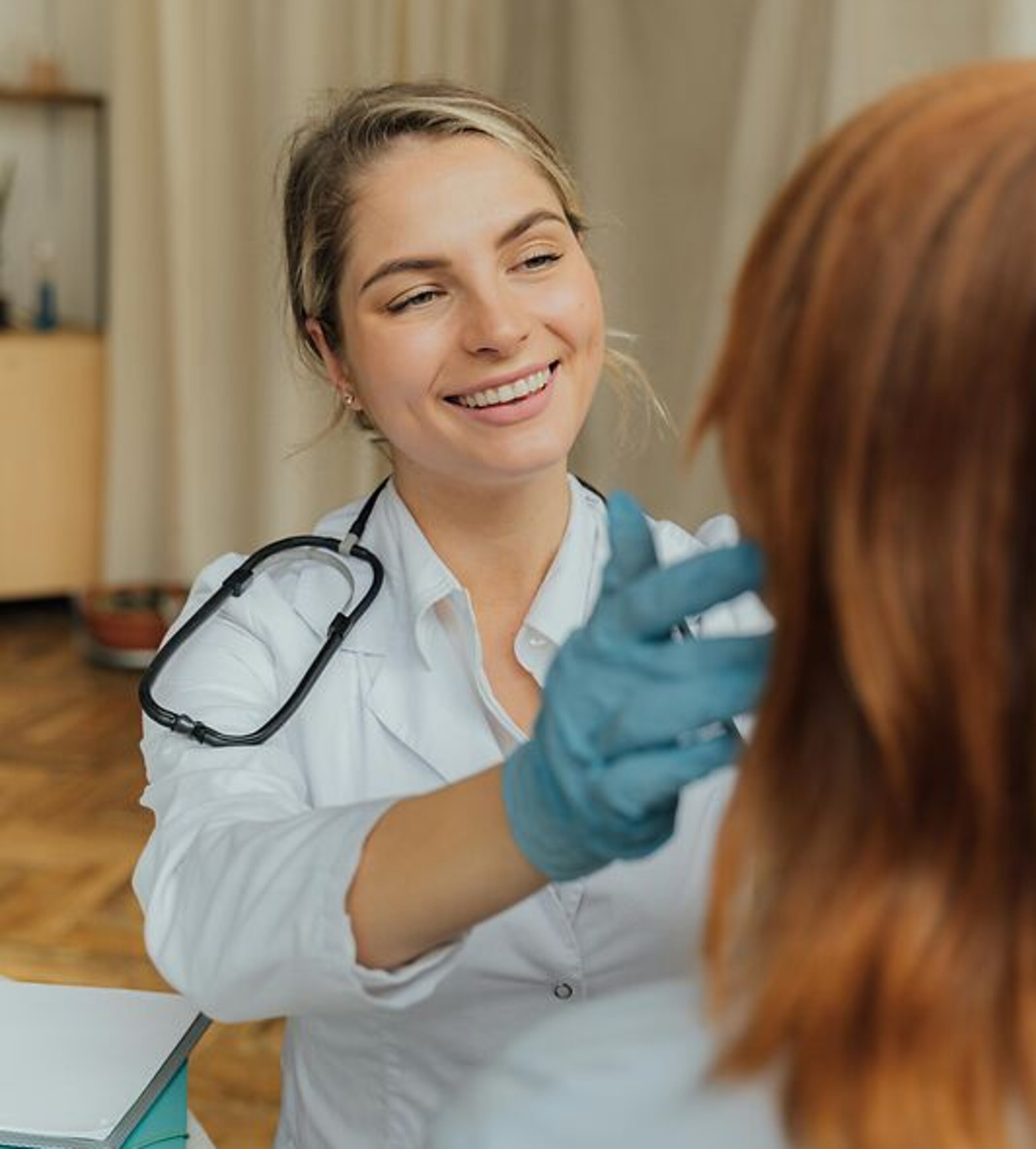 Ärztin Untersuchung Eine freundlich lächelnde Ärztin untersucht eine Patientin.