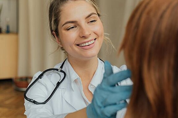 Ärztin Untersuchung Eine freundlich lächelnde Ärztin untersucht eine Patientin.