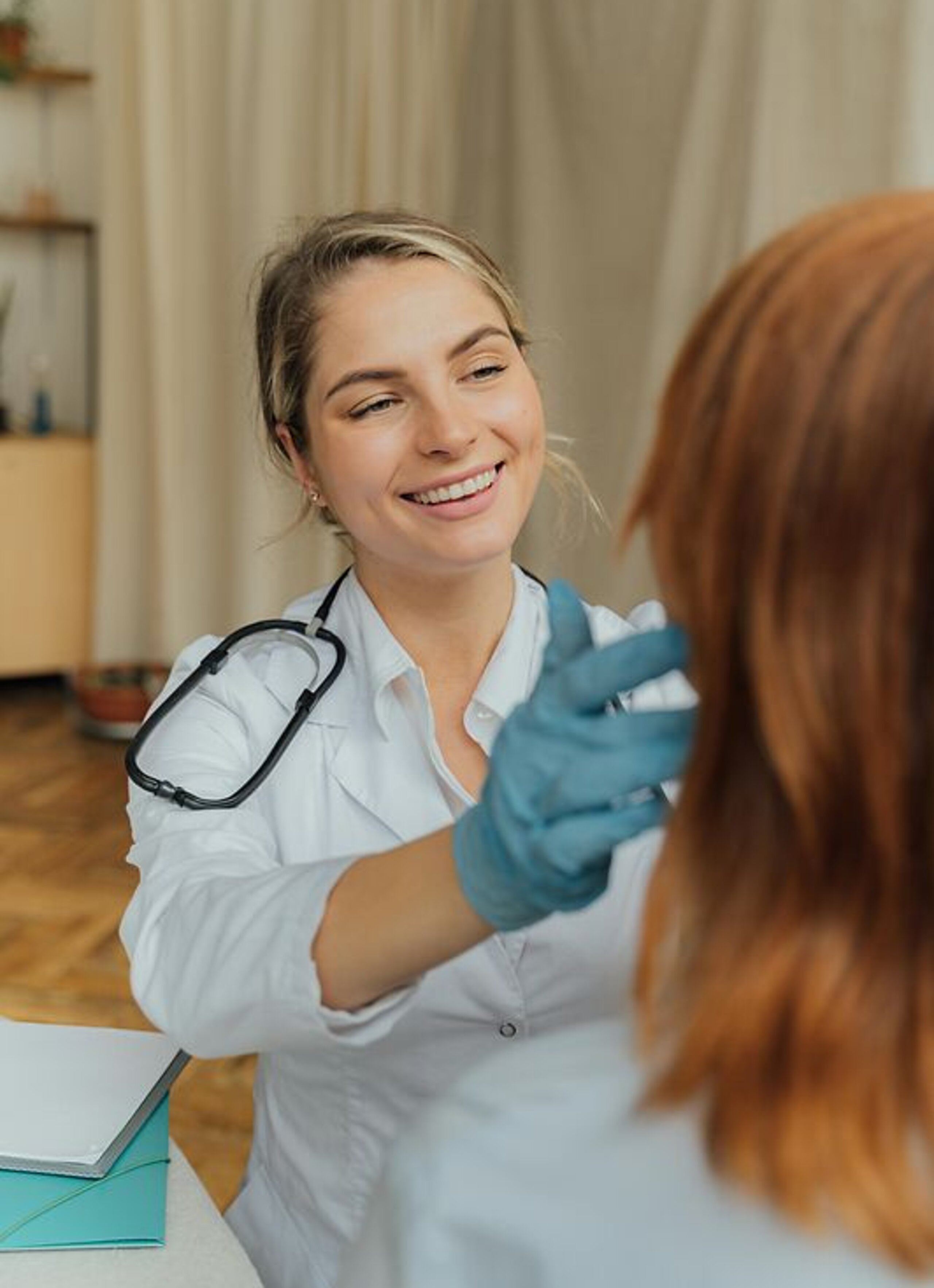 Ärztin Untersuchung Eine freundlich lächelnde Ärztin untersucht eine Patientin.