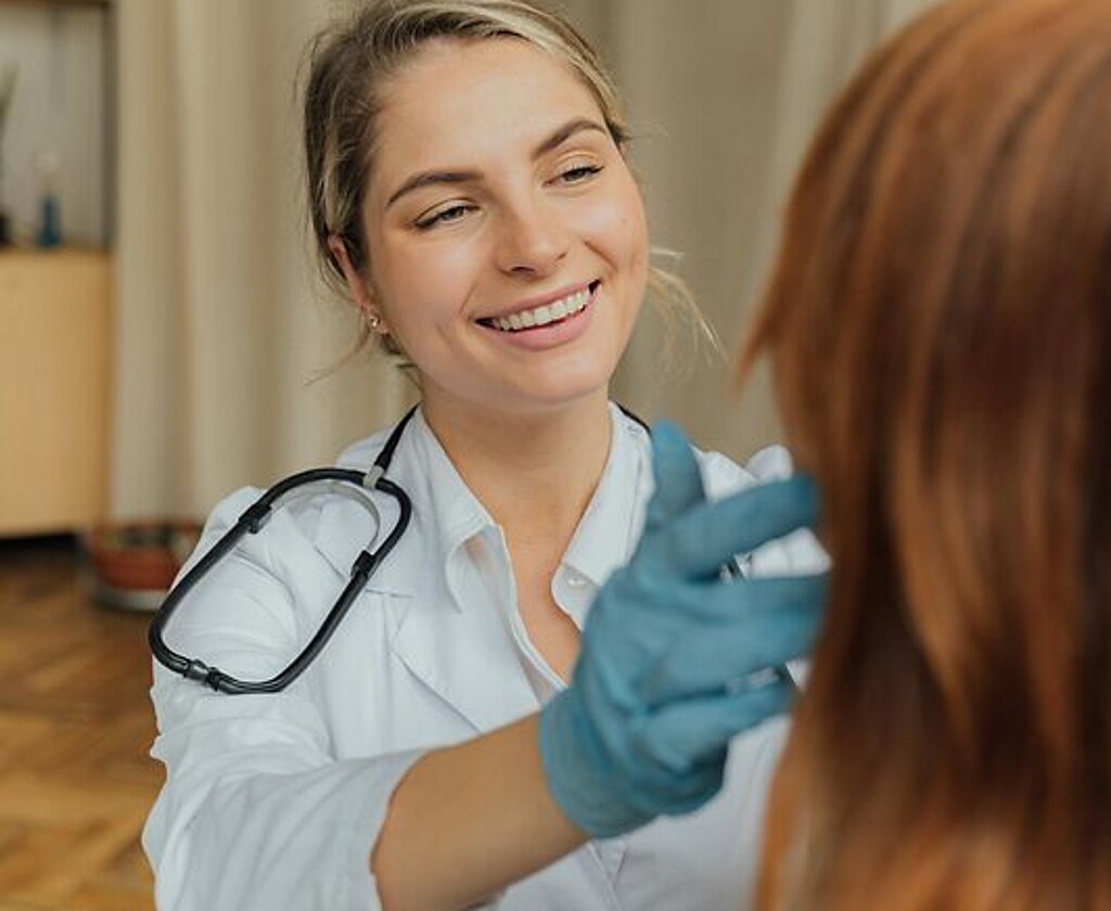 Ärztin Untersuchung Eine freundlich lächelnde Ärztin untersucht eine Patientin.