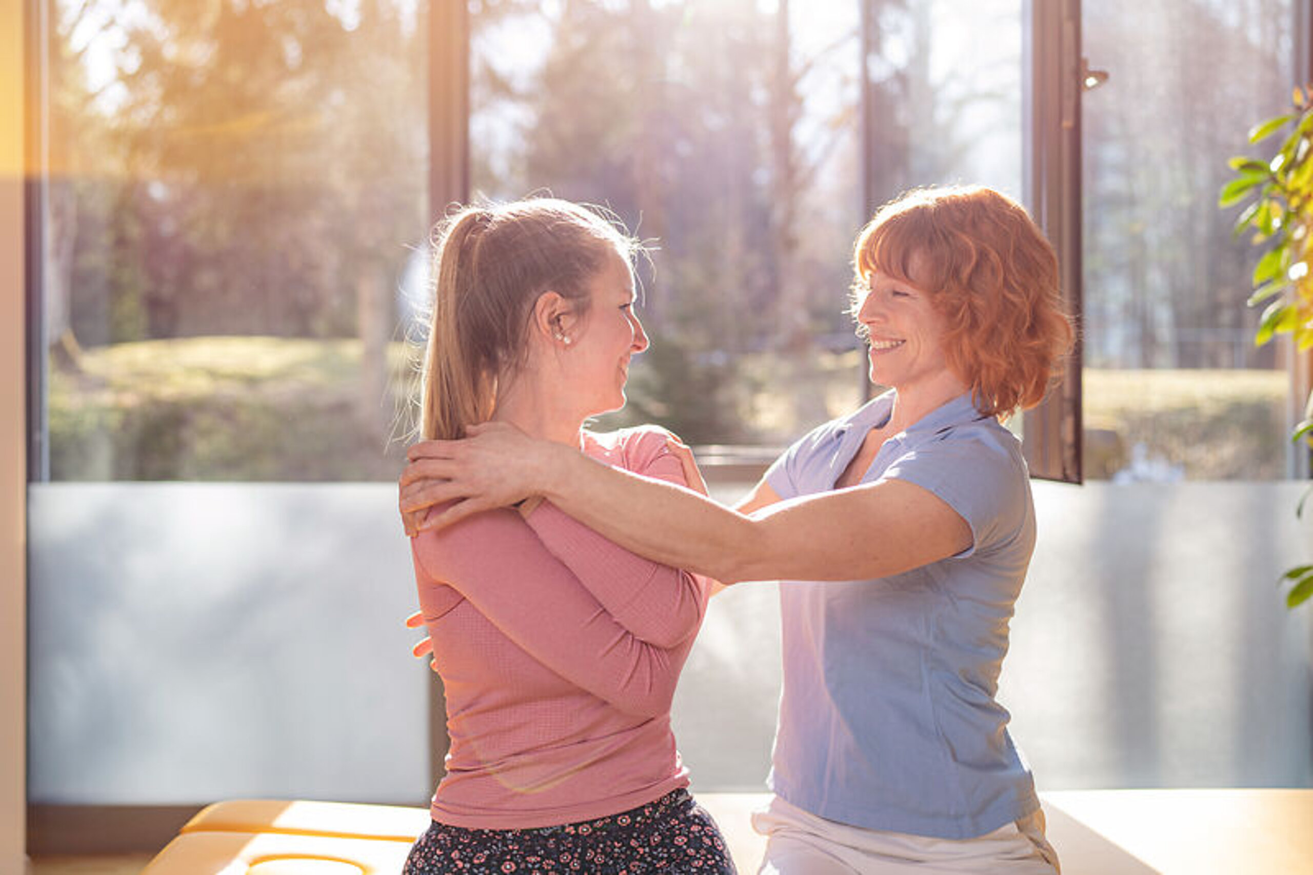 Eine Therapeutin behandelt eine junge Patientin im Sitzen.