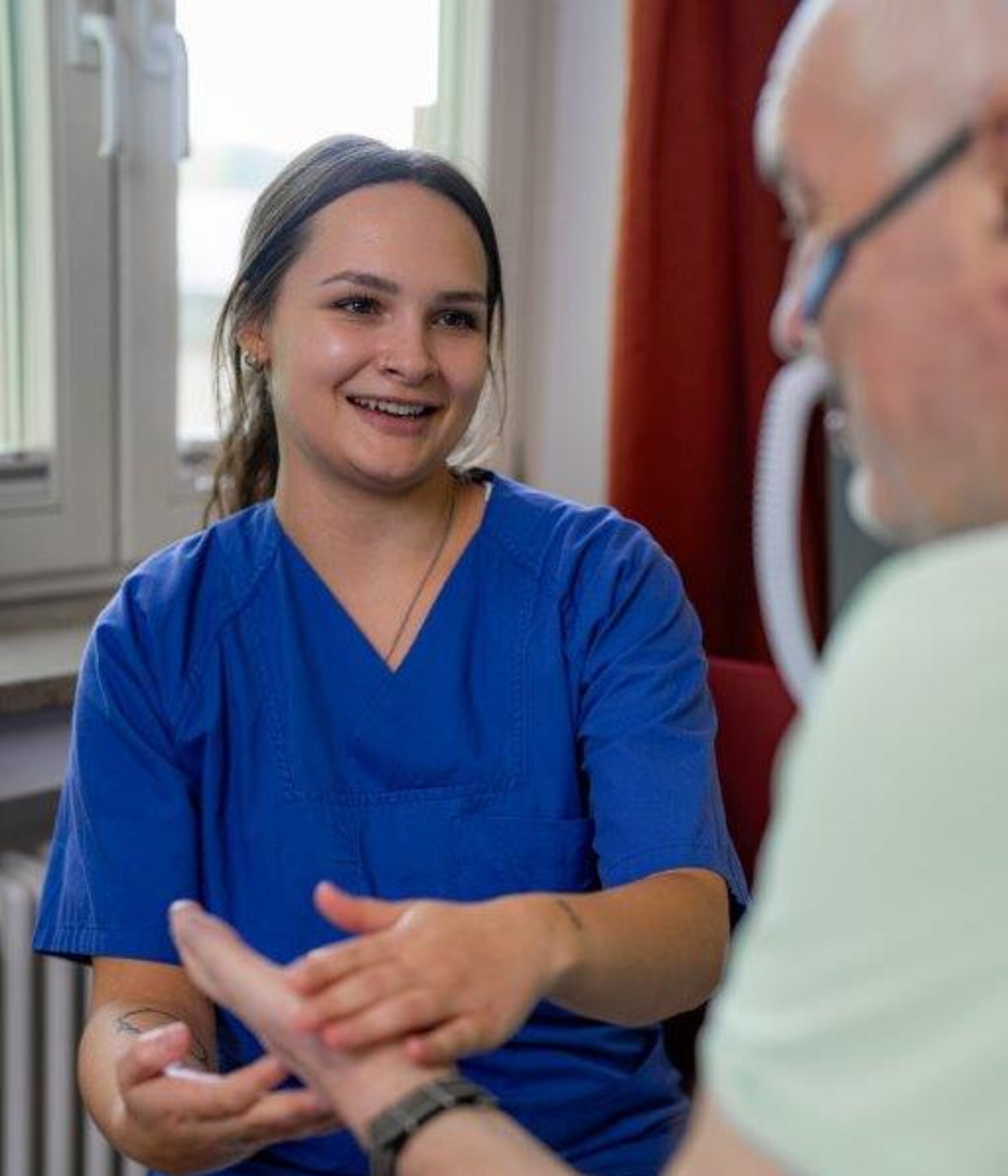 Pflegefachkraft massiert fürsorglich die Hand eines Patienten 