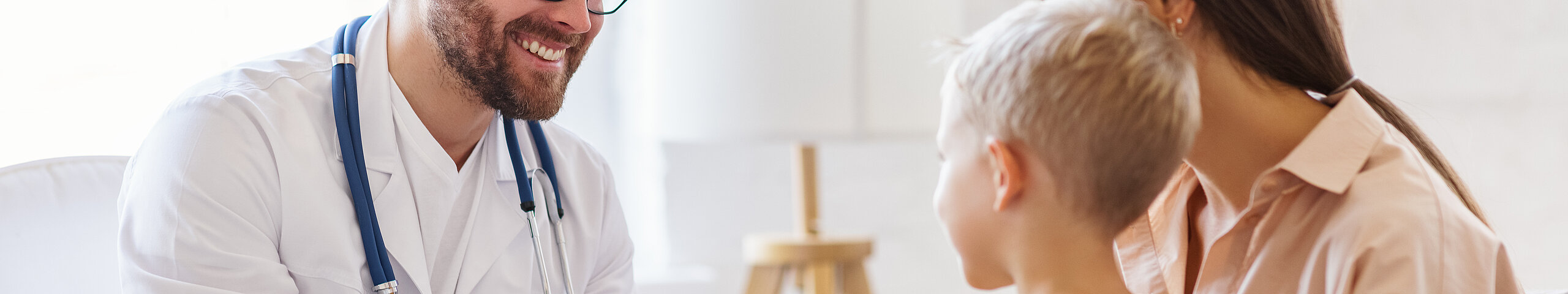 Ein freundlicher Arzt berät eine Mutter mit Sohn.