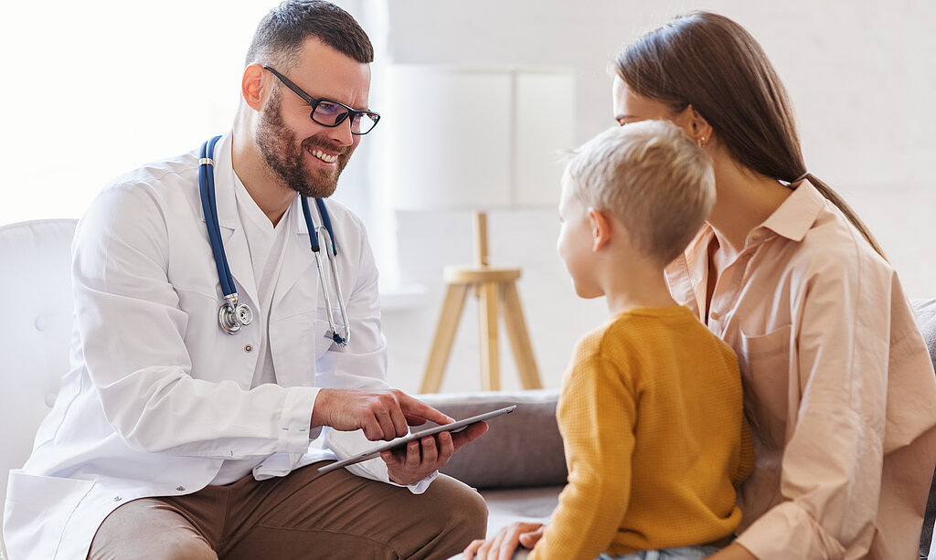 Ein freundlicher Arzt berät eine Mutter mit Sohn.