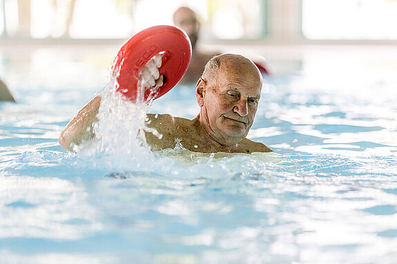 Ein Mann trainiert im Wasser mit einem Utensil.