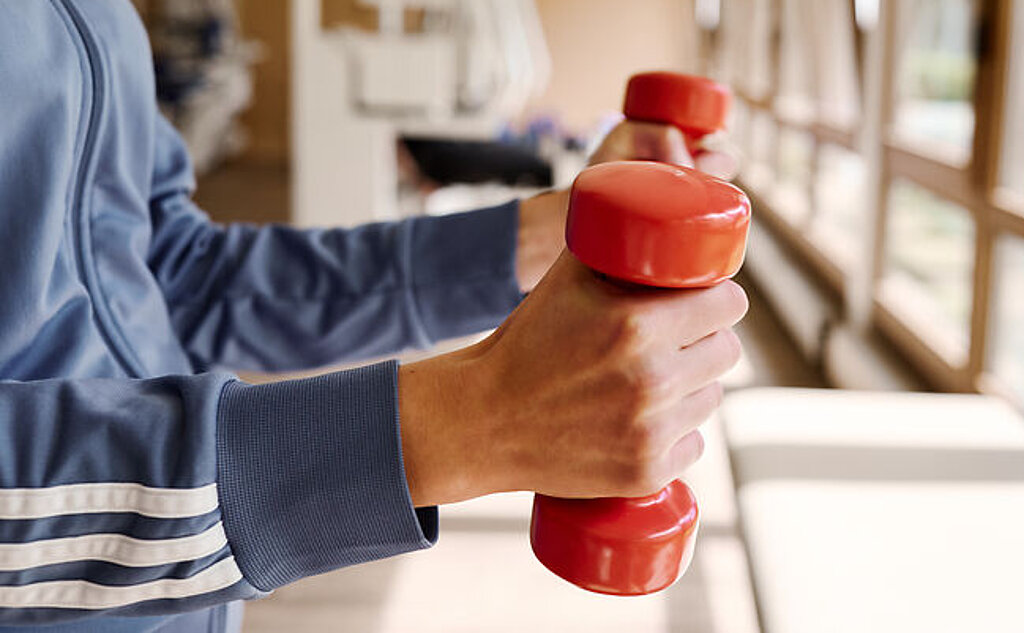 Hanteltraining Person mit Hanteln im MTT Raum.