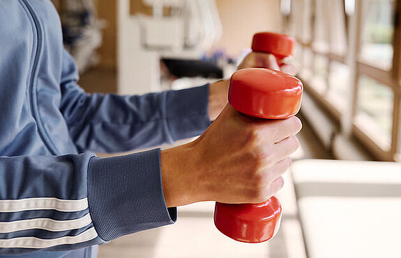 Hanteltraining Person mit Hanteln im MTT Raum.