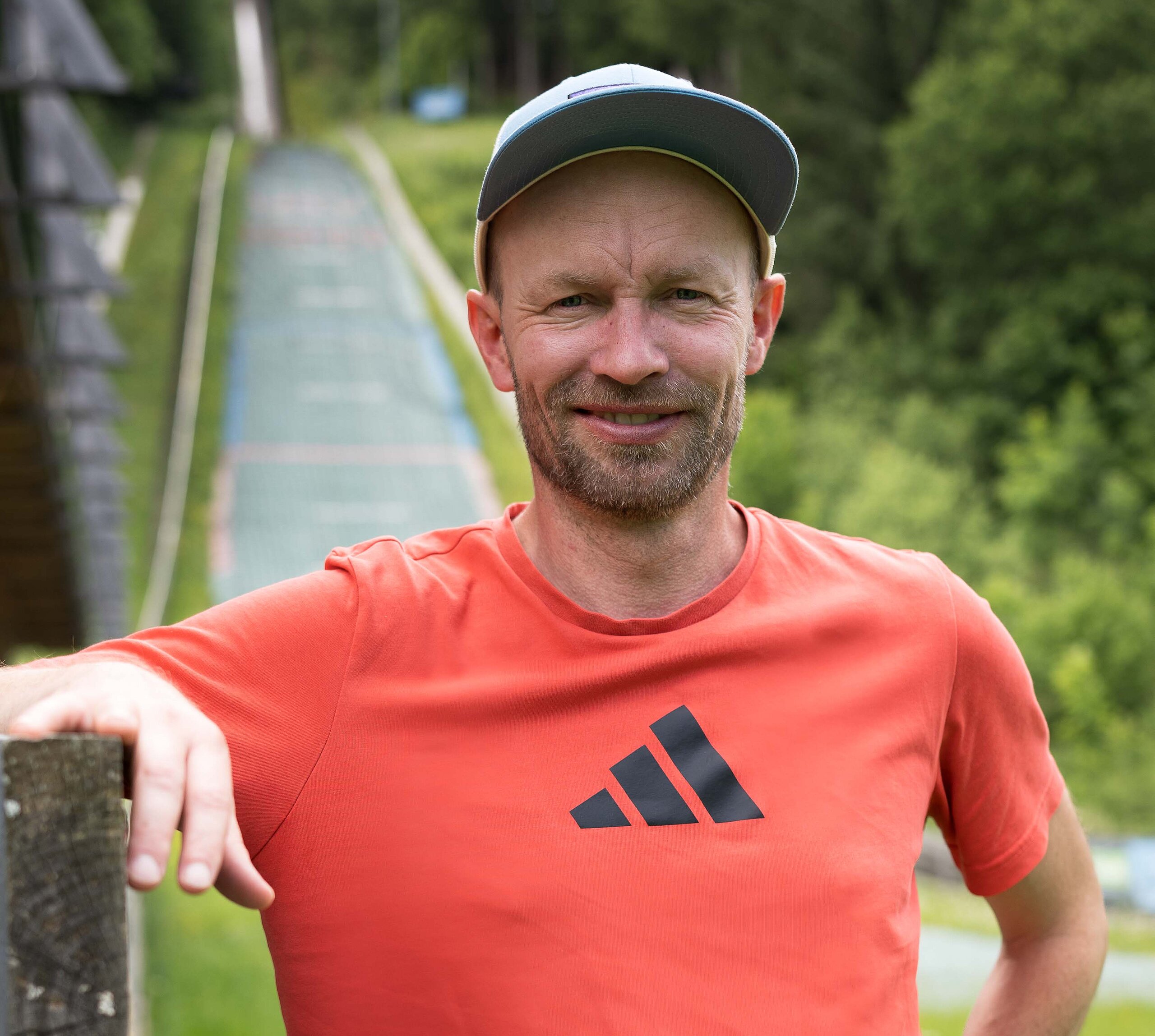 Maximilian Mechler steht vor einer Skisprungschanze.