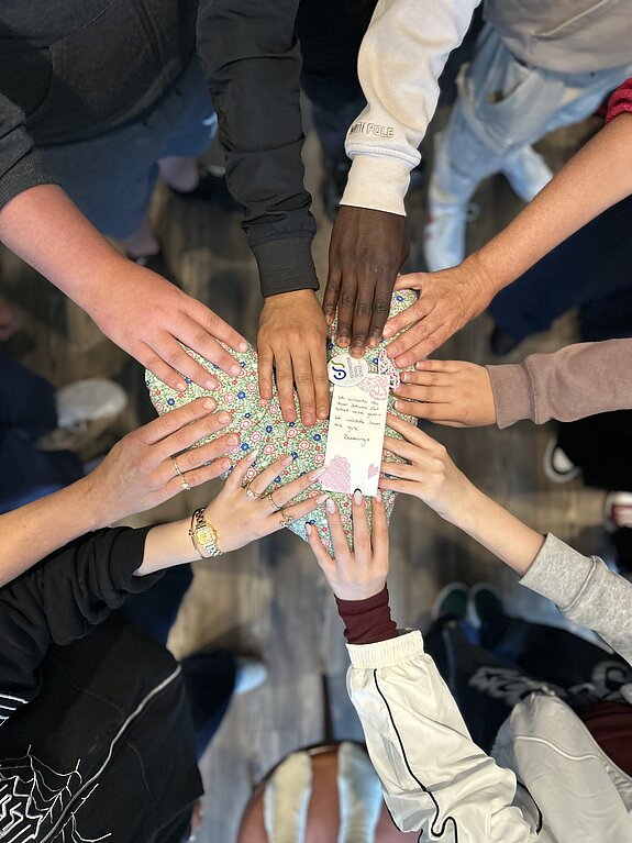 Selbst genähtes Kissen wird von vielen Händen gehalten