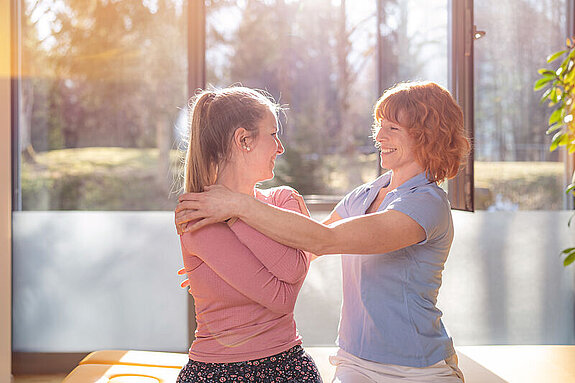 Physiotherapie Eine Therapeutin behandelt eine junge Patientin im Sitzen.