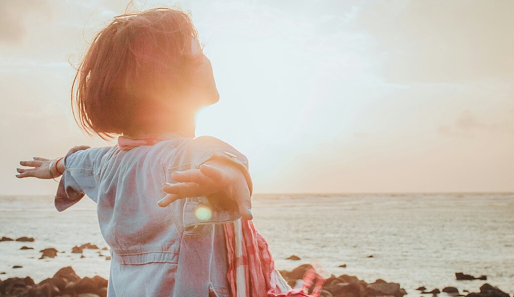 Einatmen Meer Eine Frau atmet tief ein mit ausgebreiteten Händen am Meer.