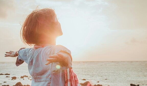 Einatmen Meer Eine Frau atmet tief ein mit ausgebreiteten Händen am Meer.