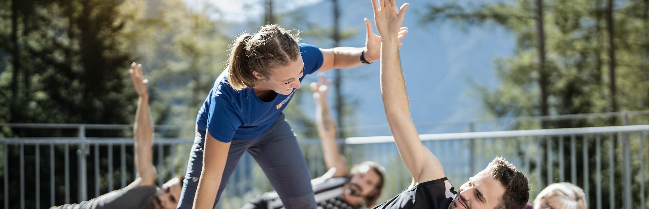 Eine Trainerin korrigiert einen Mann der in einer seitlichen Yogapose ist auf einer roten Matte