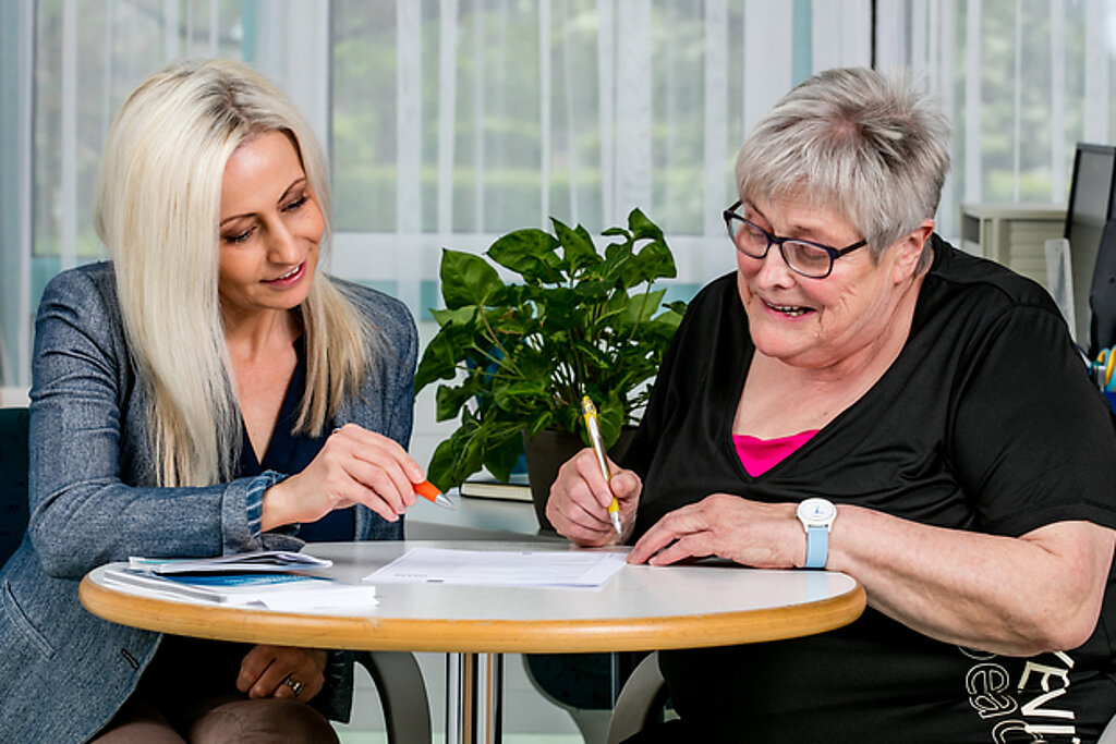 Eine Patientin füllt mit Unterstützung einer Mitarbeiterin des Sozialdienstes ein Formular aus.