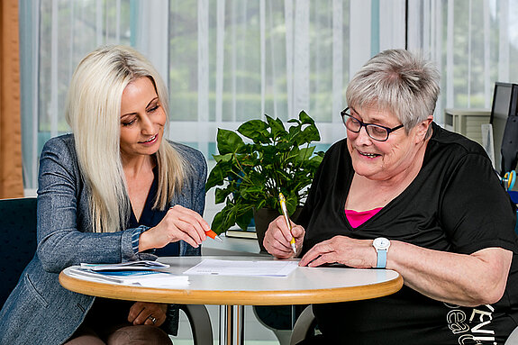 Eine Patientin füllt mit Unterstützung einer Mitarbeiterin des Sozialdienstes ein Formular aus.